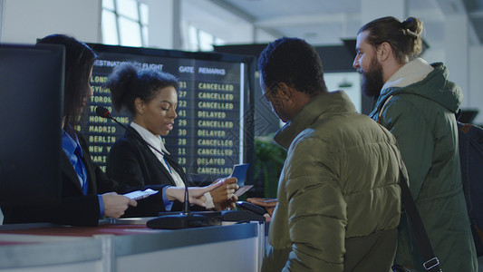 两名女机场保安人员在出发航站楼的值机柜台或登机柜台检查身份图片