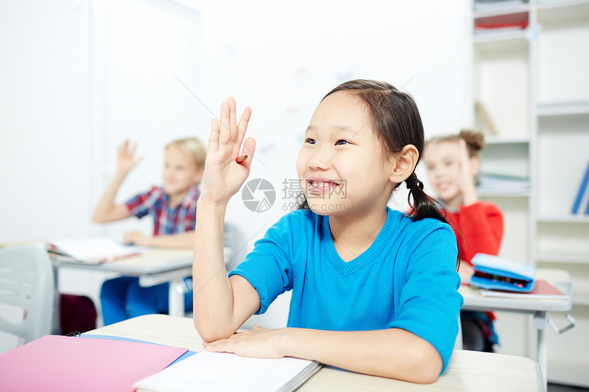 可爱的女学生和同学们在上课时举起手来图片