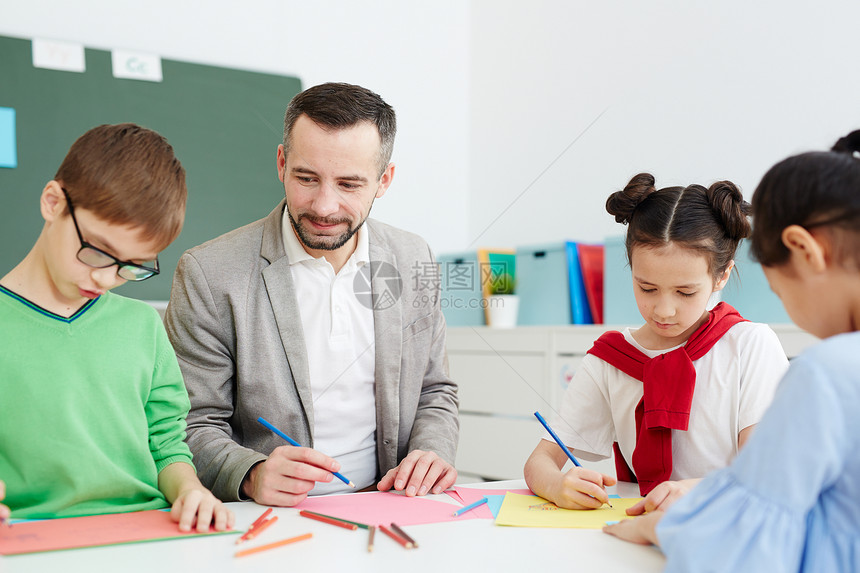 一群有创意的小学生和他们的老师坐在桌边图片