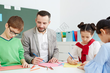 一群有创意的小学生和他们的老师坐在桌边图片