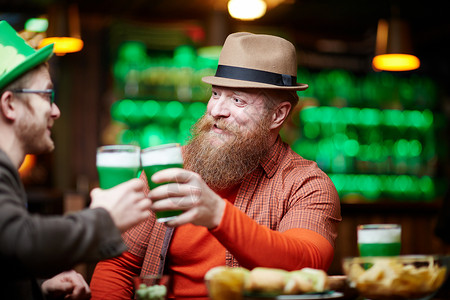 戴帽子的胡子男和同伴在酒吧放松时喝图片