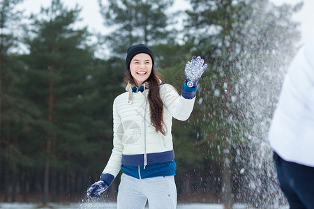 在周末户外与男友玩雪球时笑的年轻女子周末在室外图片