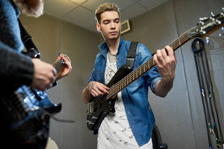 才华横溢的年轻摇滚明星音乐家在录音室与老师一起练习弹吉他图片
