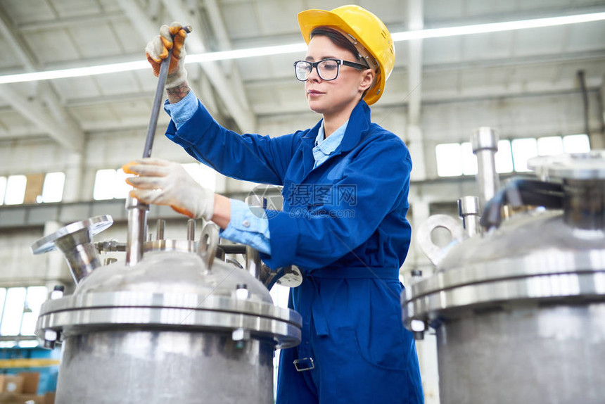 现代年轻女戴着安全帽和制服在现代工厂设置机图片