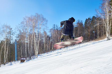 在滑雪胜地的山滑雪道上表演滑雪特技的年轻人在空中高跳跃并向图片