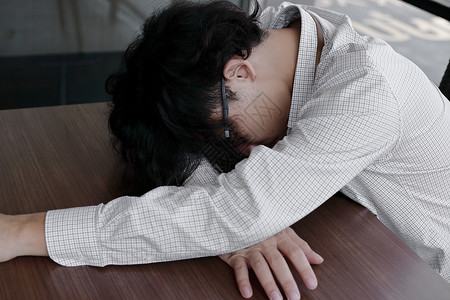 疲倦过度劳动的亚洲青年商人躺在办图片