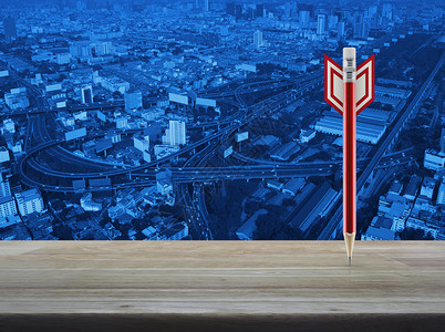 现代办公城市塔台背景商业战略概念的木桌上的红铅笔形状图片