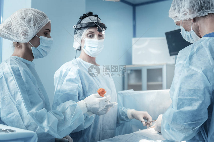 可靠的高度集中的护士站在手术室里图片