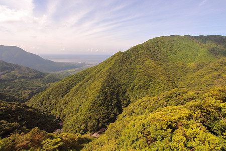 从通往日本ShirataniUnsuikyoRavine公园的公路上看到北面大片绿山和雅库岛海滨背景图片
