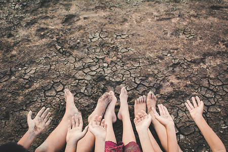 孩童的脚和手在破碎的干地上雨水感图片