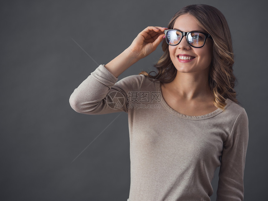 身着散衣和眼镜的迷人年轻女却在灰色背图片