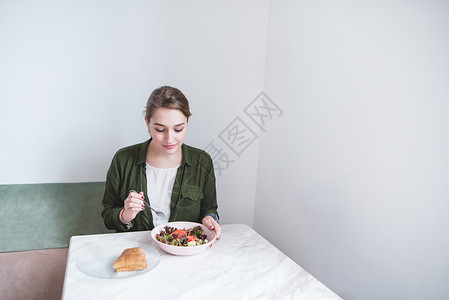 美丽的女孩坐在轻餐厅吃午餐沙拉和三明治图片