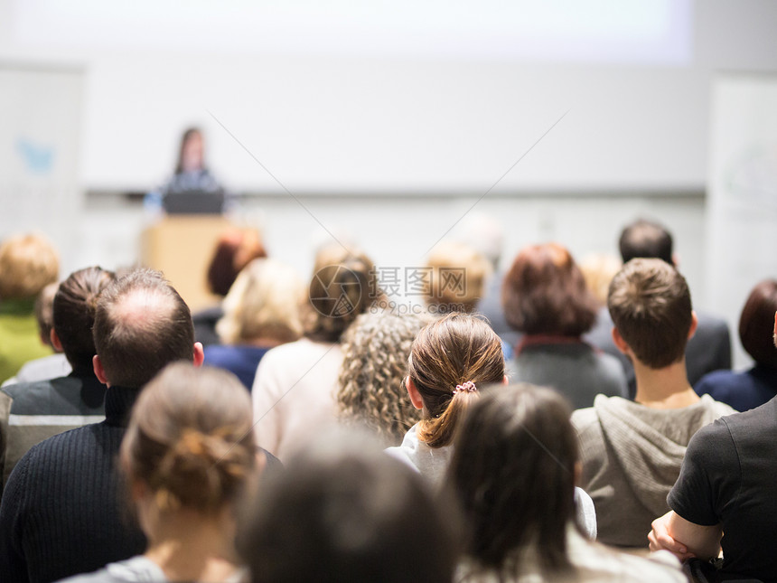 女演讲者在大学讲习班的演讲厅做演讲会议厅内的观众观众中未被识别的参与者的后视图图片