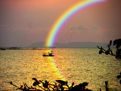 海中模糊的帆船日落天空中的彩虹和水图片