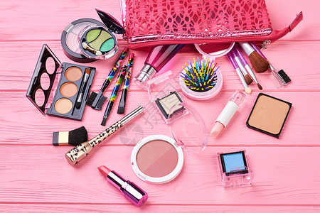 木制背景上的各种化妆产品粉红色木制背景上的装饰化妆品种粉红色的化妆包图片