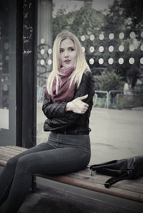 一个美丽的金发女孩坐在公共交通站图片