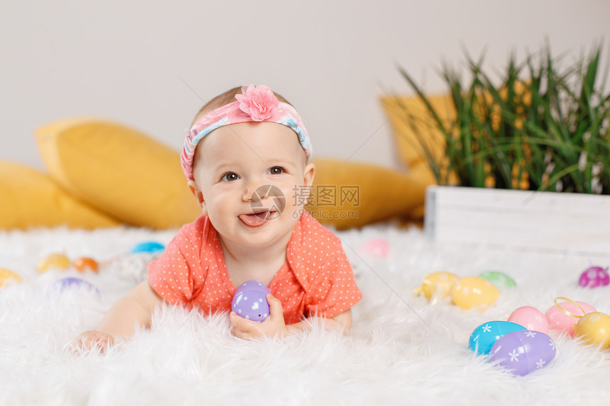 穿着红色连体衣t恤的可爱的白人女婴坐在工作室的白色柔软蓬松地毯上孩子们玩复活节彩蛋庆祝传统的神图片