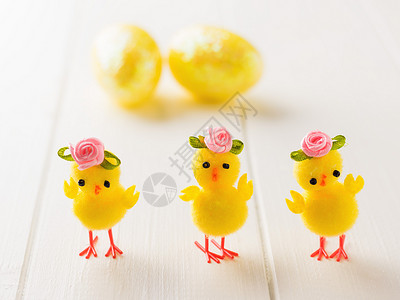三只玩具鸡和复活节鸡蛋放在白木桌上图片