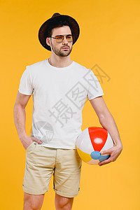 戴着帽子和太阳眼镜的年轻人拿着沙滩球图片