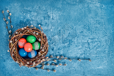 蓝色背景的复活节花环和彩色复活节蛋顶视图片