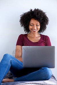 使用笔记本电脑坐在家中的非洲妇女图片