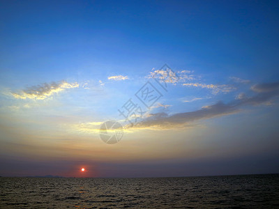 海上落日和椭圆云蓝天背景图片