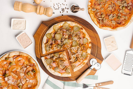 白色桌上三种披萨的顶端景色配有酱汁餐巾图片