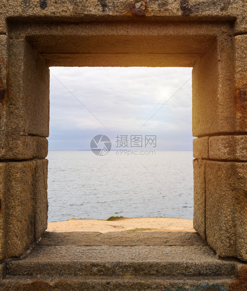 通过石墙的窗户观看的海洋图片