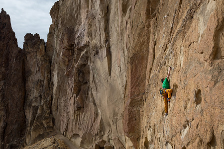 迷信的人正爬上悬崖边的岩石图片