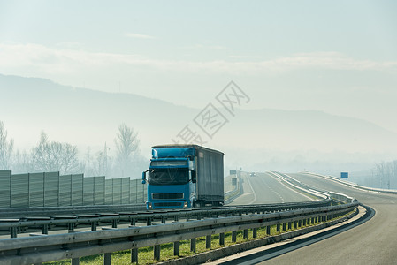 在沥青高速公路上驾驶的蓝色卡车在农村地图片