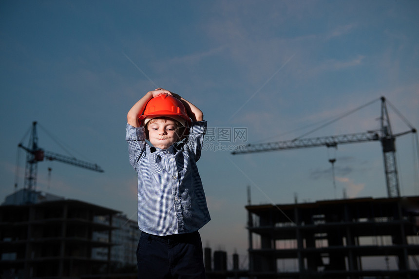 男孩在建筑起重机和建筑大楼的背景下图片