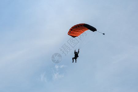 与橙降落伞对抗蓝天的伞兵图片