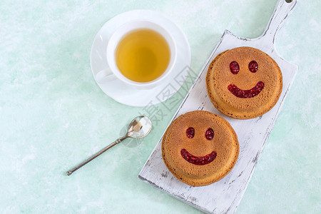 以笑脸和一杯茶的形式有趣的纸杯蛋糕引起积极情绪的食物幽默的甜食好心情美背景图片
