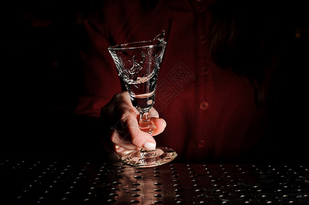 妇女手握鸡尾酒杯在酒吧柜台装满一杯图片