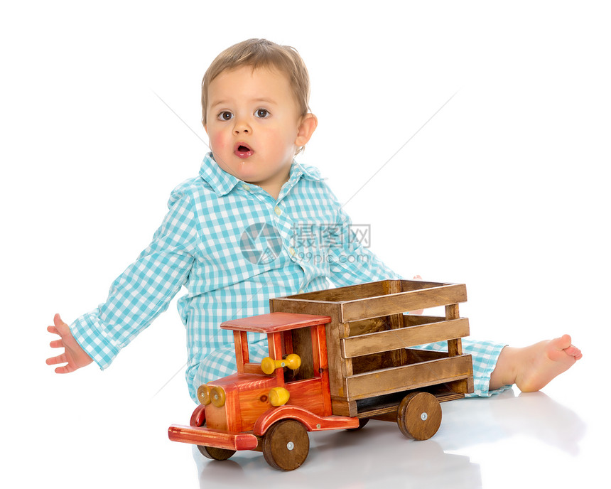 可爱的小男孩正在工作室里玩白色背景的玩具木车快乐童年家庭和教育图片