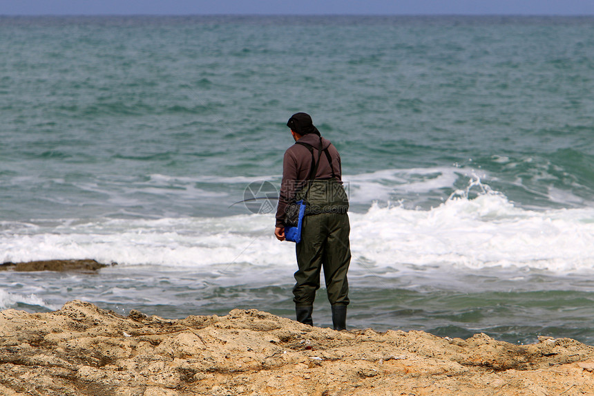 渔夫坐在岸边抓鱼图片