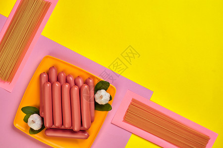 黄色和粉红色最小背景上橙色盘子上的香肠平躺顶视图静图片