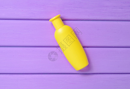 紫色木桌上的一瓶黄色洗发水图片