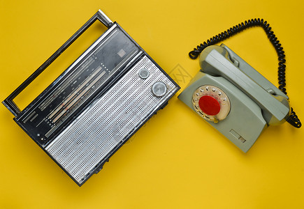 70年代文化黄色背景的无线电接收器和旋转电话反转图片