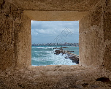 石窗框俯瞰地中海亚历山大市旧东港的屏障和入口背景图片
