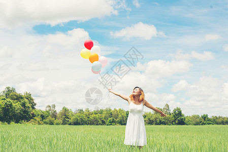 美丽的年轻女士快乐在草地上有气球享图片