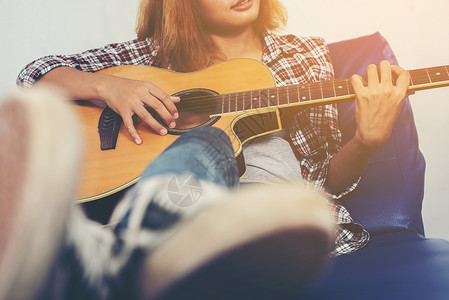 年轻的时髦女人弹吉他背景图片