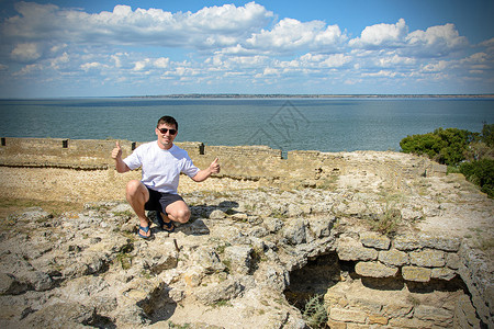 戴墨镜的年轻人坐在海边堡垒的墙上敖德萨阿克曼堡垒的墙图片