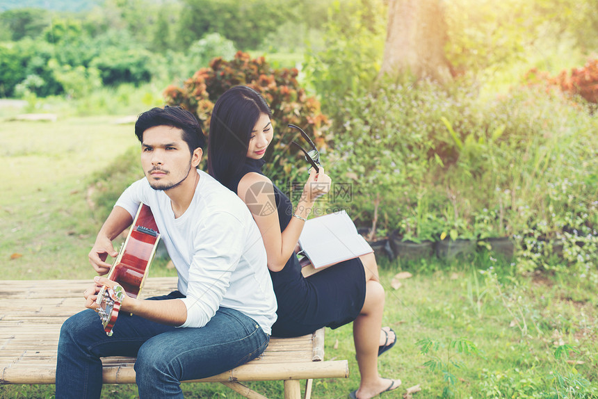 年轻迷人的情侣恋爱在公园里弹吉他图片