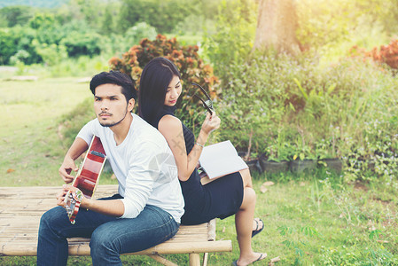 年轻迷人的情侣恋爱在公园里弹吉他图片