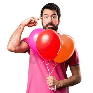 英俊的年轻男子疯狂的姿态拿着气球在孤立图片
