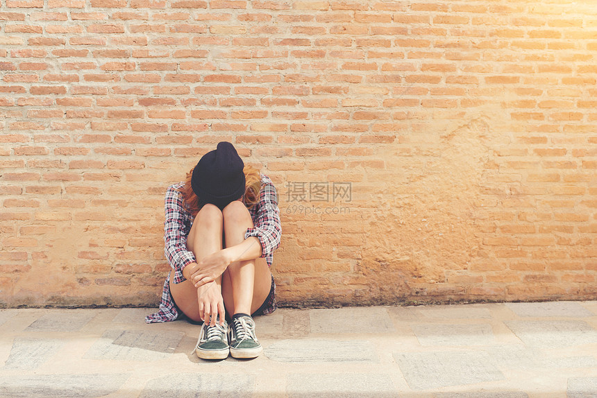 少妇伤心地独自坐在砖墙上图片