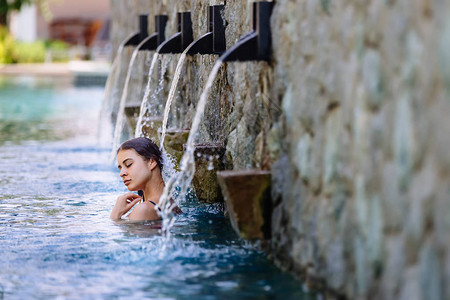 妇女利用游泳池在豪华海滩滨酒店度假胜地享受假期图片