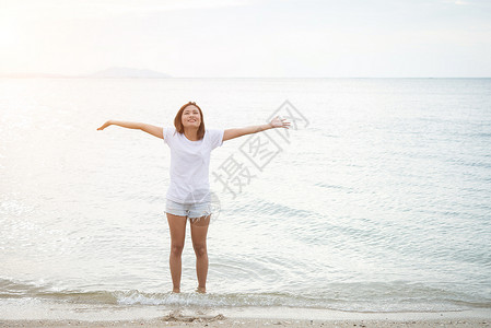 年轻漂亮的女人赤脚站在海滩上图片