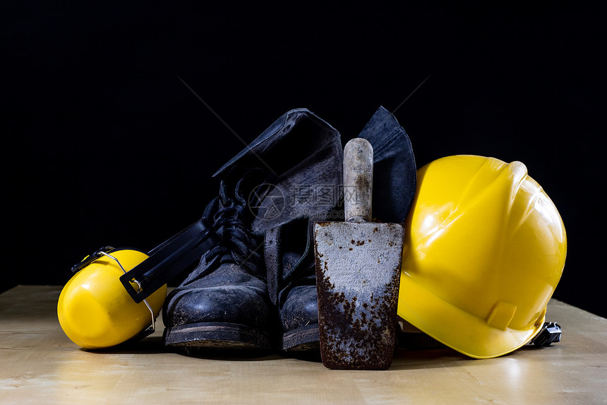 工作台桌旁的防护服和工具建筑工人的购买和头盔黑色背景单图片